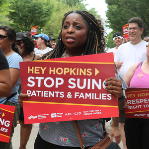 Woman holds sign "Stop suing patients and families"