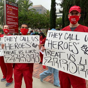 Nurses hold signs "They call us heroes but treat us like zeroes"