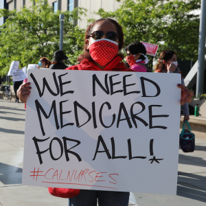 Nurse holding sign "We need Medicare for All"