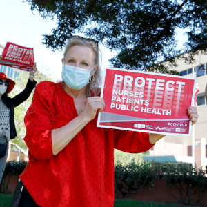 Nurse holds sign "Protect Nurses, Patients, Public Health"