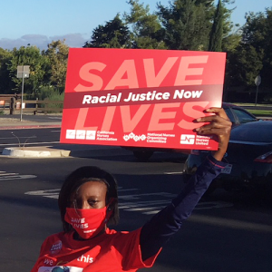 Nurse holds sign "Racial Justice Now"