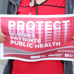 Nurse holds "Protect Nurses" sign