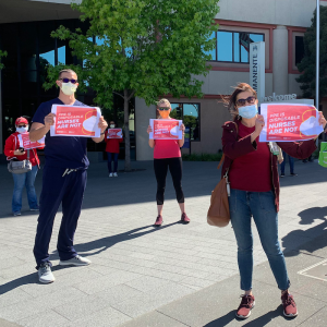 Nurses hold signs "PPE is disposable, nurses are not"