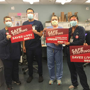 Nurses hold signs "Safe Staffing Saves Lives"