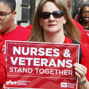 Nurse holds sign "Nurses and Veterans Stand Together"