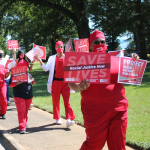 Nurses holds signs "Racial Justice Now" and "Protect Nurses"