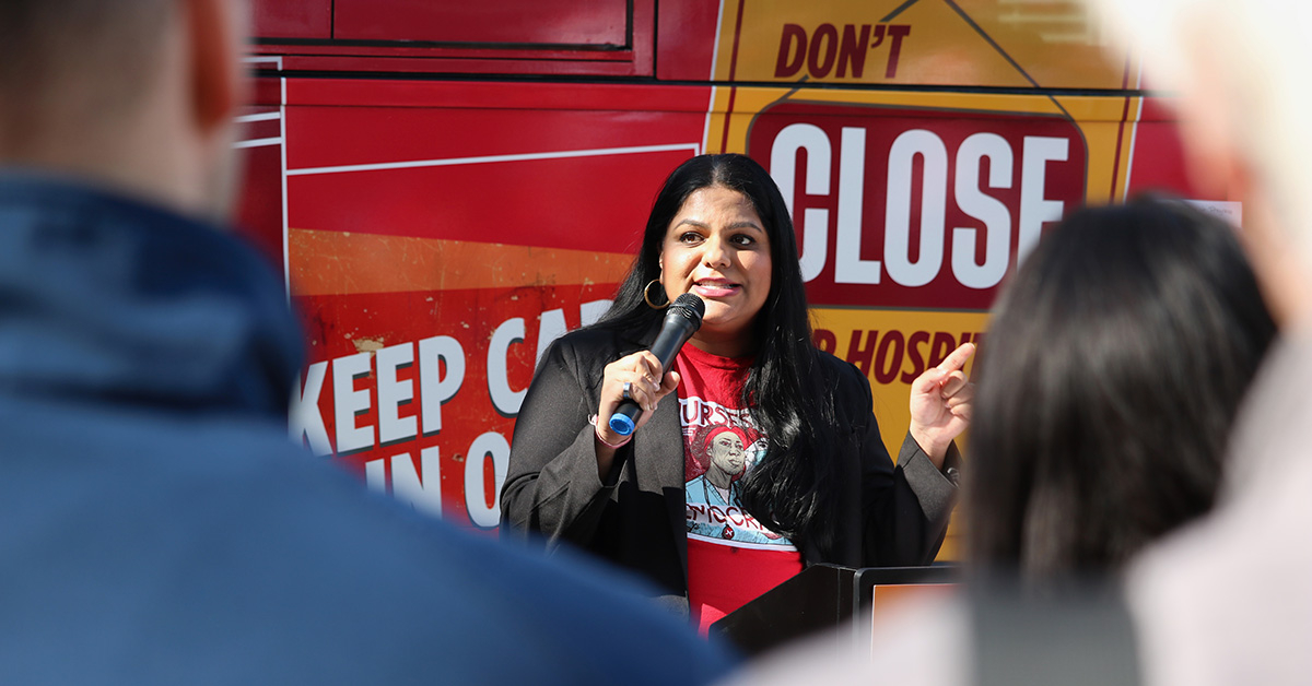 NNU Executive Director Puneet Maharaj standing with microphone in front of Red Alert tour bus