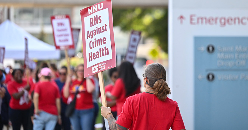 Nurse holds sign "RNs Against Crime Healthcare"