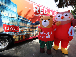 Medi Bear and Nurse Owl character infaltable costumes outside Red ALert tour bus