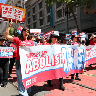Nurse hold "Nurses say abolish ICE!" banner at rally