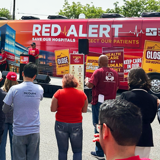 Community at Red Alert Tour stop with red alert bus in background