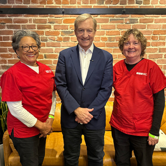 Two nurse leaders posing, smiling with Tom Steyer