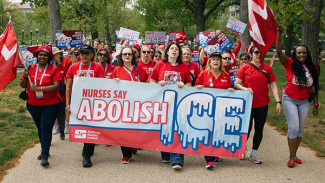 Nurses marching, holding banner "Nurses Say Abolish ICE"