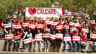 Large group of people holding CalCare signs and banner