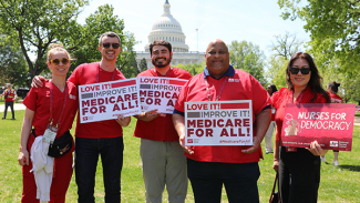 Five nurses in red, standing outside D.C. Capitol building, three holding signs "Medicare for All"