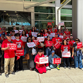 Large group of nurses outside hospital holding signs "Defend DACA Nurses" and "Protect DACA Nurses Now!"