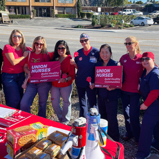 Large group of nurses outside, picketing, with signs "Union nurses build healthy communities" 