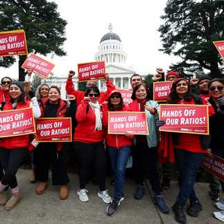 Group of nurses outside California State Capitol building holding signs "Hands Off Our Ratios"