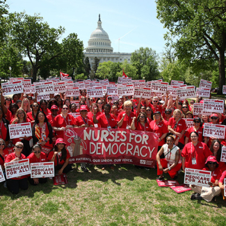 Large group of nurses in Washington D.C., holding signs "Medicare for All" and banner "Nurses for Democracy"