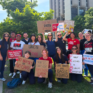 Large group of nurses outside holding signs calling for union rights, patient care, and an end to hospital greed