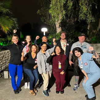 Group of nurses outside, at night, smiling, with raised fists