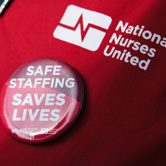 National Nurses United scrub with button 'Safe Staffing Saves Lives | NNOC/NNU'