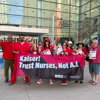 Group of nurses outside, with raised fists, holding banner "Kaiser! Trust Nurses Not A.I."