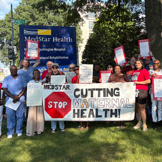 Large group of nurses and community members outside MedStar hospital holding banner "MedStar: Stop Cutting Maternal Health"