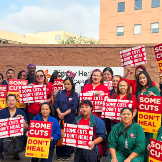 Group of CommonSpirit nurses with signs "Some Cuts Don't Heal"