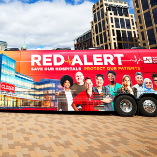 Picture of Red Alert tour bus against city backdrop
