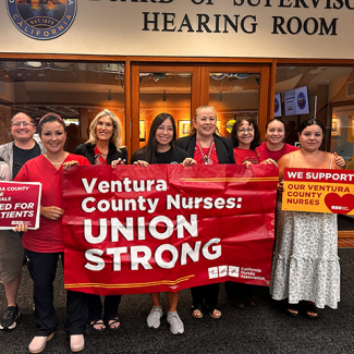 Group of nurses inside, smiling, holding banner "Ventura County Nurses: Union Strong"