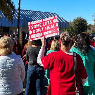 Watsonville nurse, staff, community, holding sign "Some cuts don't heal"