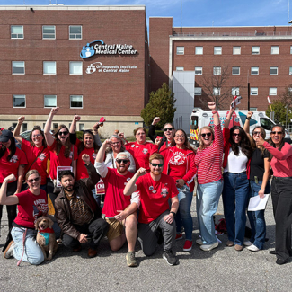 Group of nurses outside hospital, smiling, with raised fists
