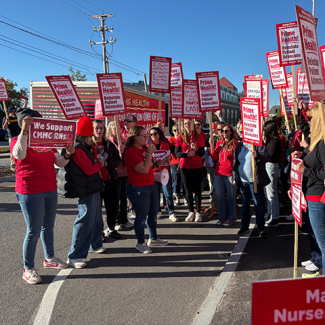 Large group of nurses rallying holding signs "Prime Health: Reinstate Patient Advocates"
