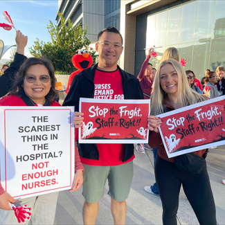 Three nurses outside smiling, holding signs "Stop the Fright, Staff it Right"