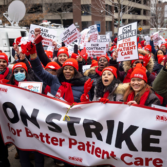 NYSNA nurses marching with signs and banners "On strike for better patient care"