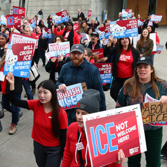 Nurses marching holding signs "ICE Not Welcome Here"