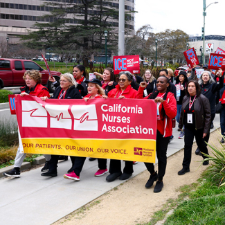 Nurses marching holding signs "ICE Not Welcome Here" and banner "California Nurses Association"