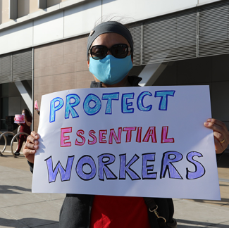 Nurse holds sign "Protect Essential Workers"