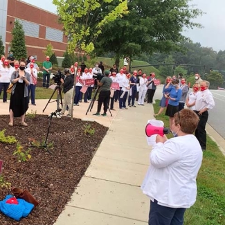 Group of nurses outside Mission Hospital, one speaking into megaphone