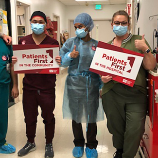 Nurses in hallway holding signs "Patients First in the Community" "Patients First in the Hospital"