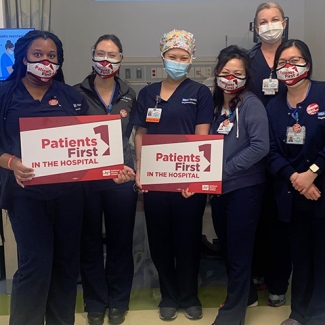 Group of nurses inside hospital hold signs "Patients First in the Hospital"