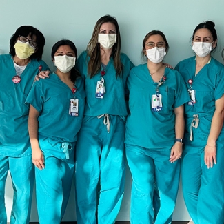 Group of six nurses standing side-by-side inside hospital