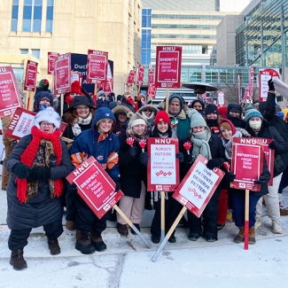 Large group of nurses outside UChicago in cold weather holding signs calling for dignity and respect