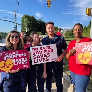 Four nurses outside holding signs "Safe Staffing Saves Lives"