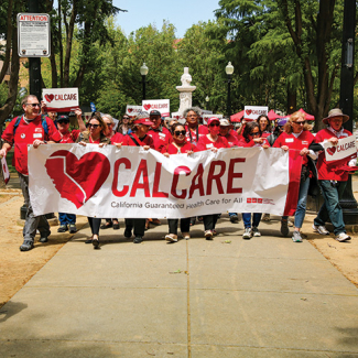 Group of nurses in scrubs marching holding "CalCare"