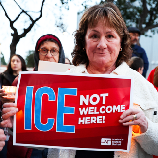 Person holding sign "ICE NOT welcome here"