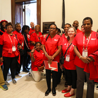 Group of nurses in red scrubs outside congressional office