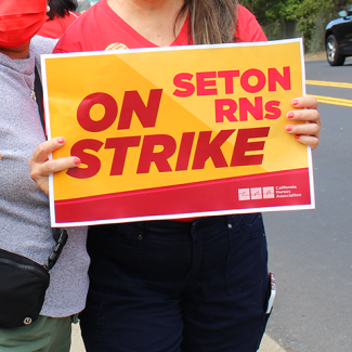 Nurse holding sign: Seton RNs on STRIKE