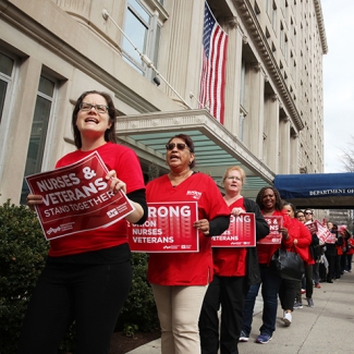 Nurses outside VA office hold signs "Nurses and Veterans Stand Together"